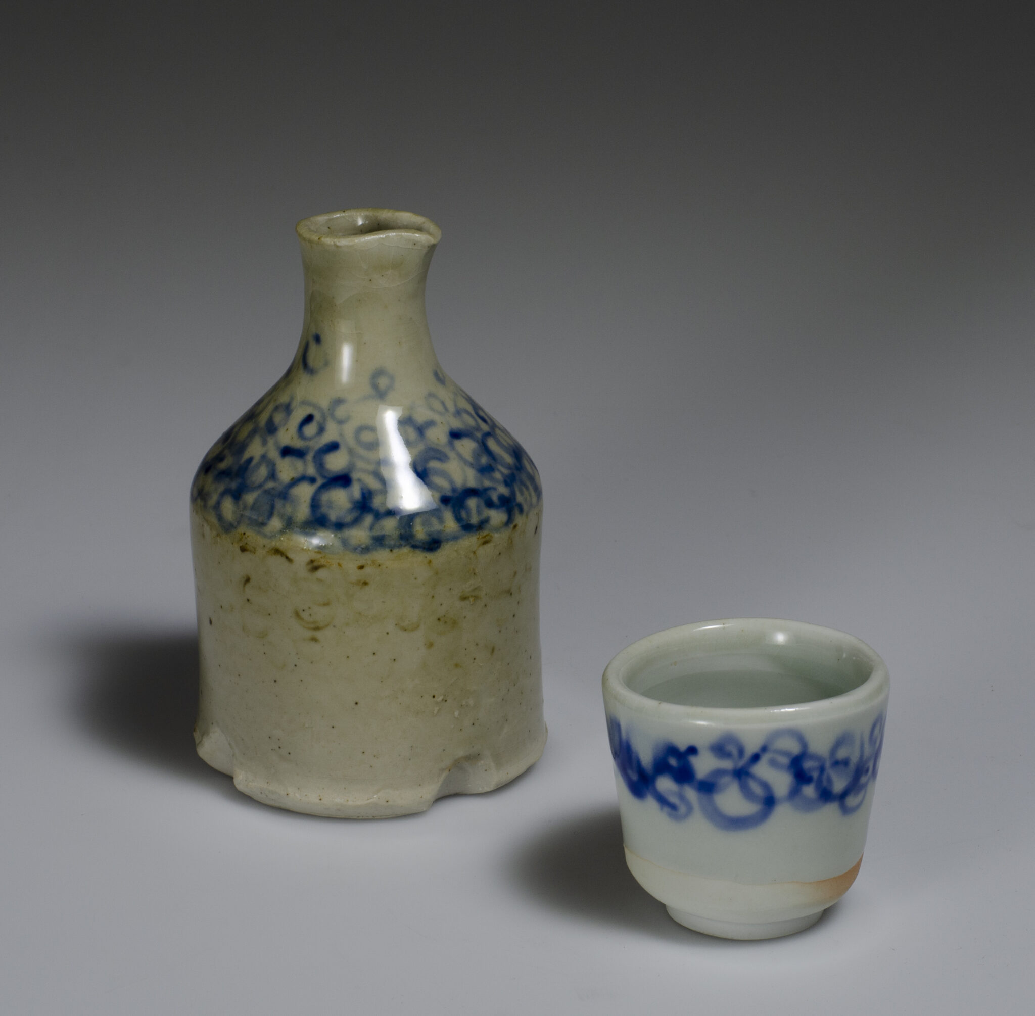 wood fired white porcelain tea bowl and pitcher with blue circle pattern underglaze and celadon glaze