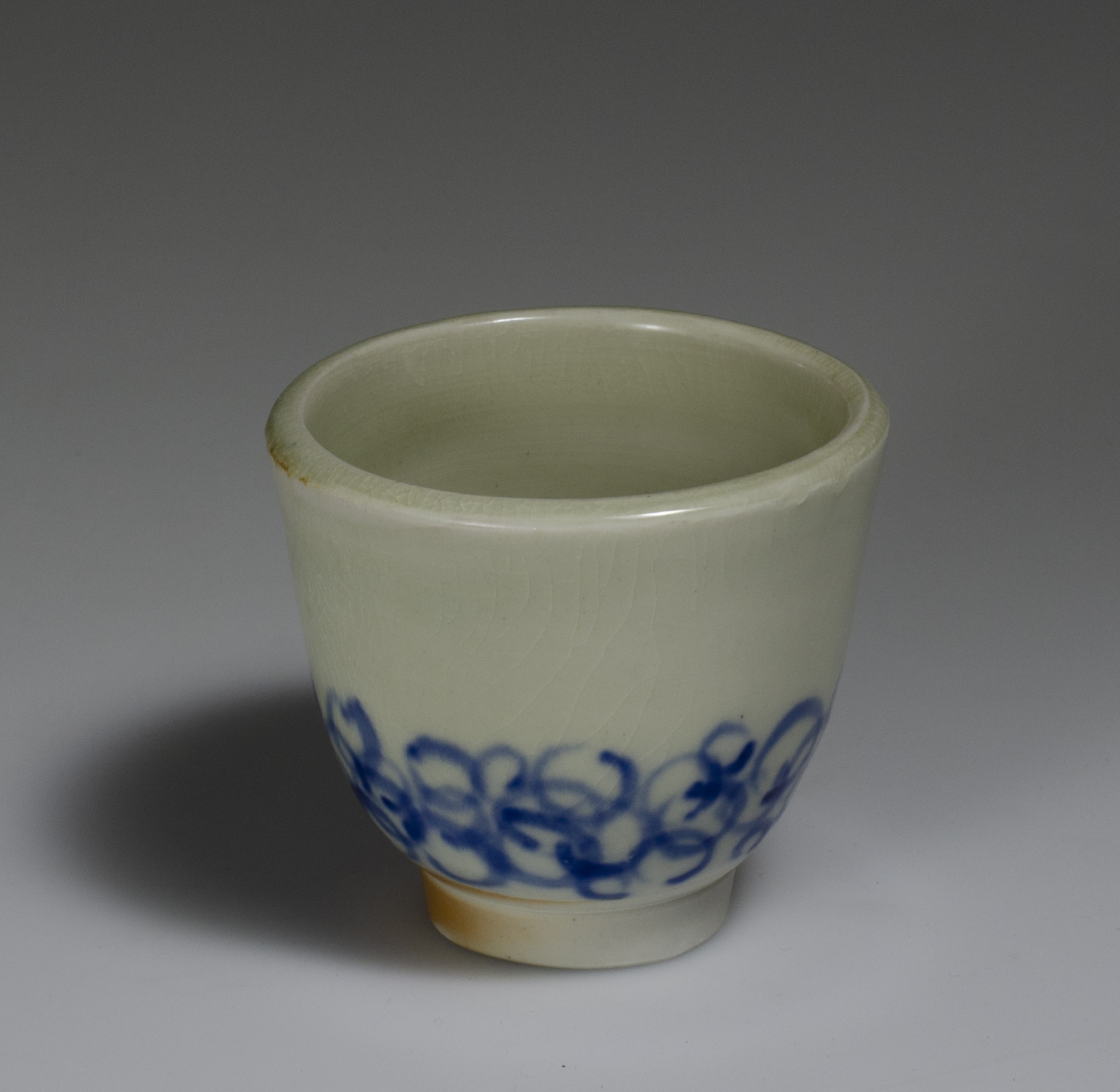 wood fired white porcelain tea bowl with blue circle pattern underglaze and celadon glaze